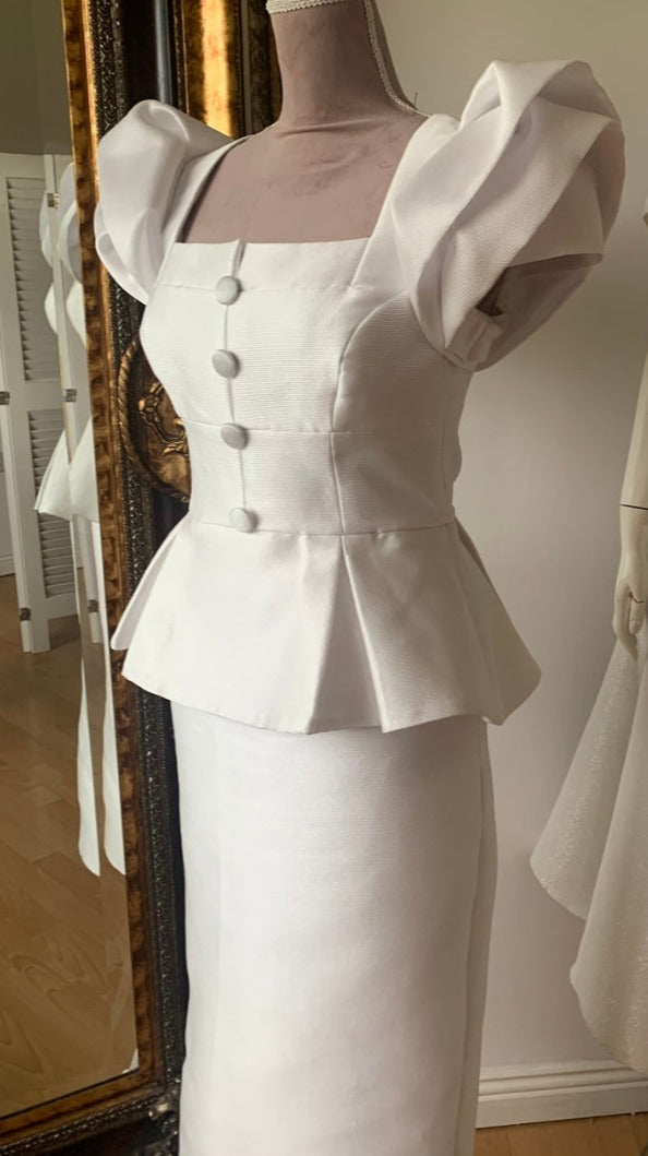 Carmen Sydney Two Piece Skirt & Top suit. Made in a light texture Mikado Ivory Fabric, fully lined in Satin. Featuring button front detail and Dramatic Shoulder in a Layered Rose Effect.