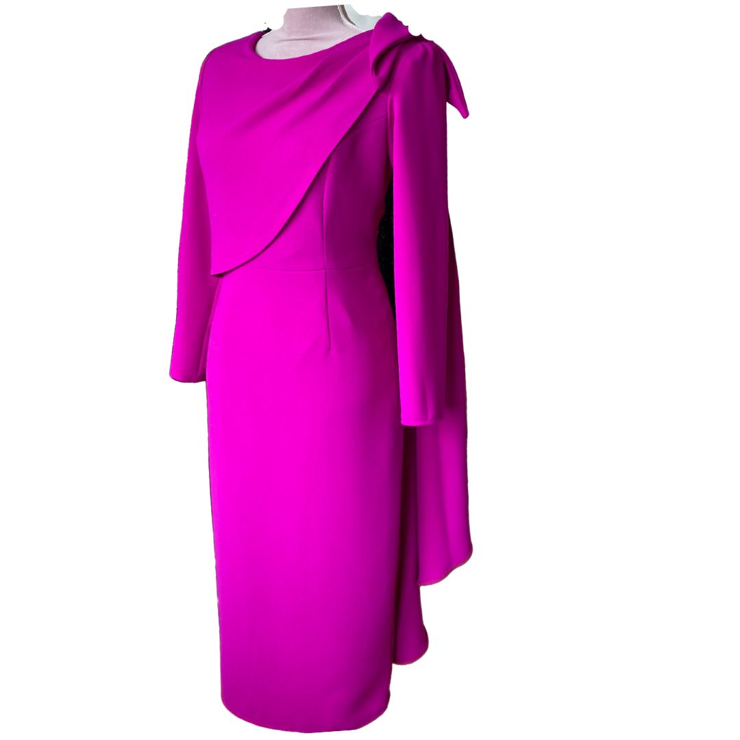 This fitted dress in high quality fuchsia crepe has a flattering drape across the bust that extends over the shoulder in a Bow detail and down the back creating a little extra drama for a special occasion. The dress has ¾ sleeves and is fully lined in satin with a back zip. 