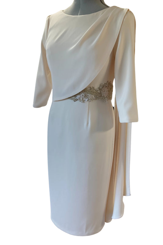 This tailored dress is made in high quality Warm Ivory crepe and has a flattering drape across the bust that extends over the shoulder. The drape detail cascades down the back creating a little extra drama for a special occasion along with the detailed applique that can be on the waist or the shoulder. The dress has three quarter sleeves and is fully lined in satin with a back zip.
