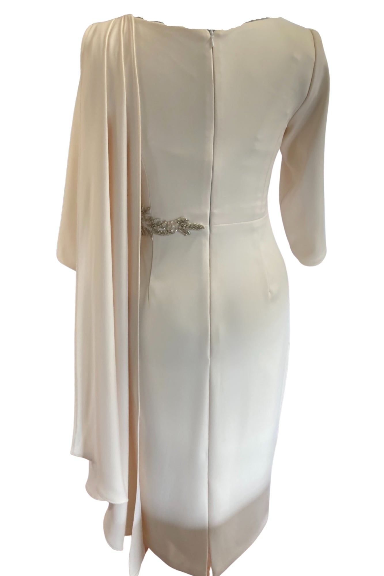 This tailored dress is made in high quality Warm Ivory crepe and has a flattering drape across the bust that extends over the shoulder. The drape detail cascades down the back creating a little extra drama for a special occasion along with the detailed applique that can be on the waist or the shoulder. The dress has three quarter sleeves and is fully lined in satin with a back zip.