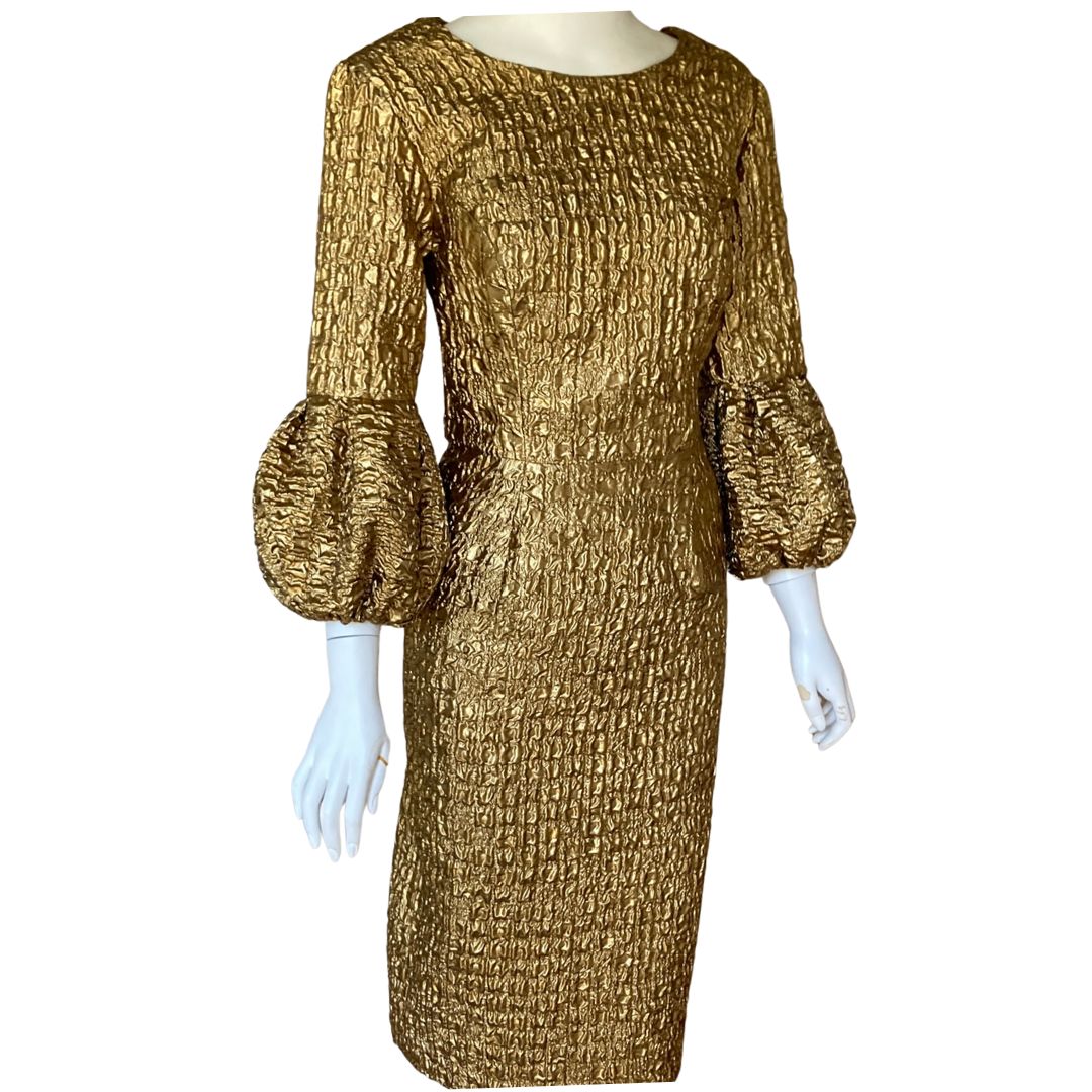 This Metallic Gold Embossed Jacquard Shift Dress gives a very simple line while offering a unique twist with a volume cuff. The luxurious fabric is incredibly lightweight, and the metallic finish elevates the dress to a special occasion. Fully Lined in Satin with concealed zip at the back.